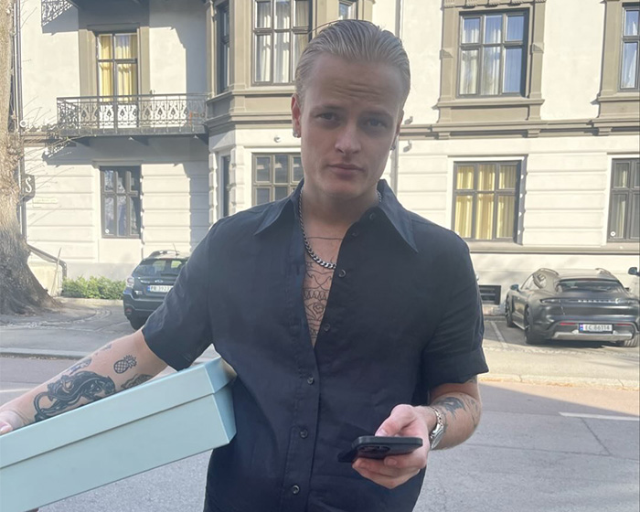 Marius Borg H&oslash;iby, son of Norway's Crown, holding a box and phone, despite conviction on multiple serious offenses.