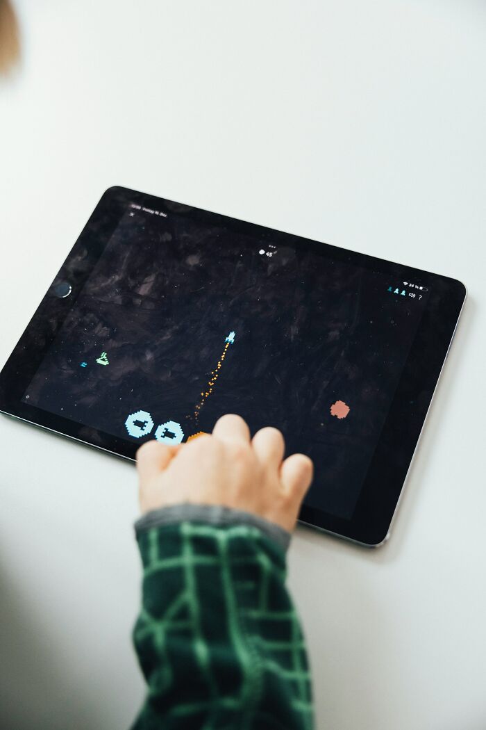 A child plays a video game on a tablet, showcasing the surprising pain reactions related to screen time.