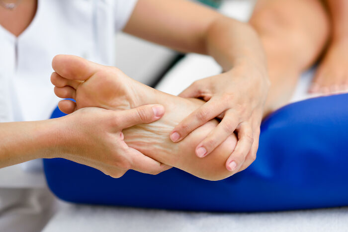 A close-up of hands massaging a foot, illustrating the specific care often linked to childhood beliefs about health.
