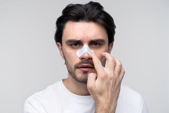 A man applying a pore strip to his nose, representing sweet and funny patient stories of self-care