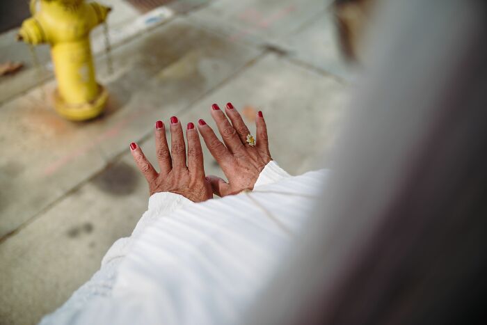 An older patient showing off bright red nail polish and a ring to medical workers
