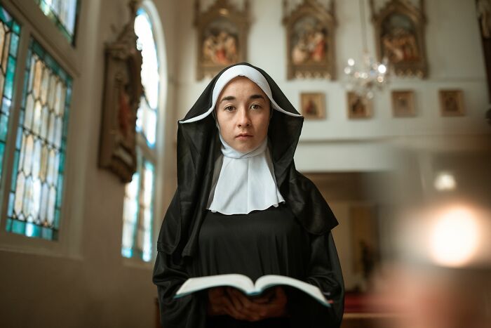 A nun holding an open book symbolizing strange stories