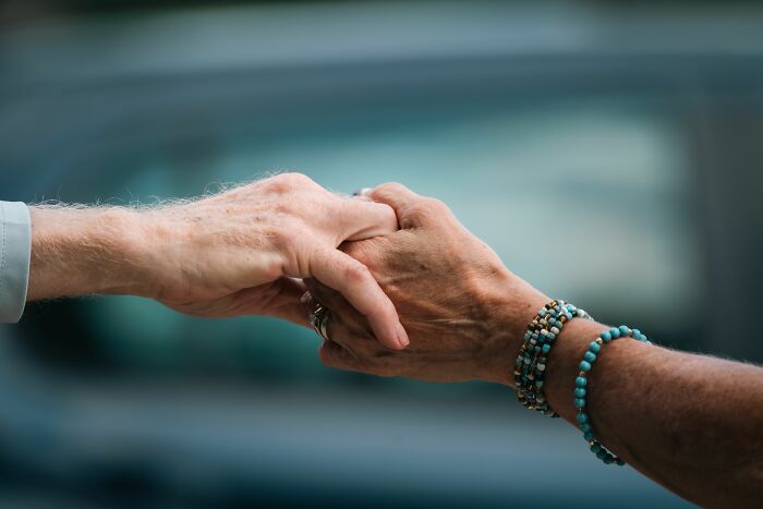 Close up of two elderly people holding hands, illustrating touching medical patient stories.