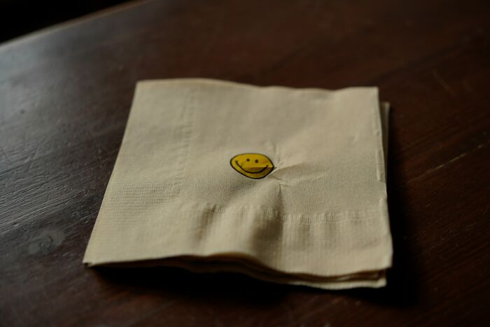 A simple paper napkin with a small yellow smiley face, representing sweet patient stories.