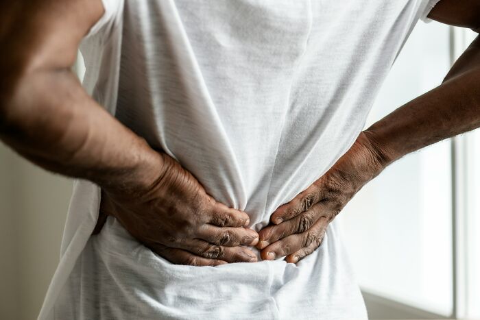 A medical worker or patient holds their lower back in pain, highlighting medical patient stories.