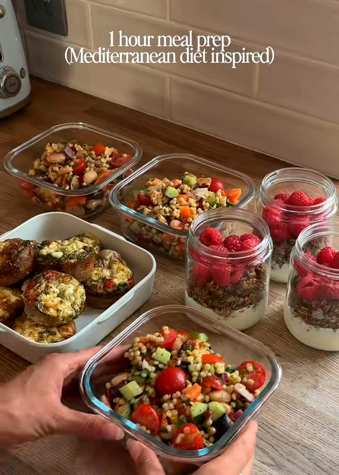 An array of meal prep containers filled with Mediterranean diet inspired dishes like salads, yogurt, and berries.