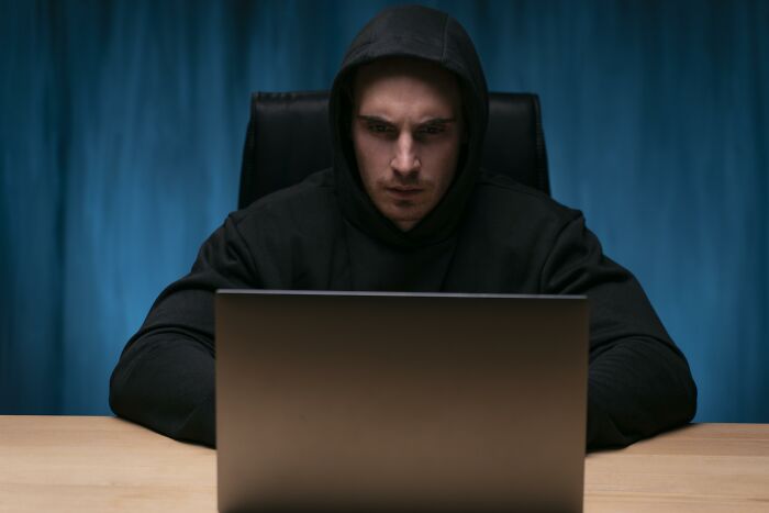 A focused man in a black hoodie looking at his laptop screen, illustrating stories of people who said nothing