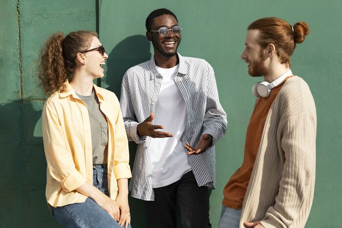 Three friends laughing together outdoors, highlighting experiences of subtle sexism.