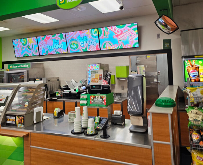 Subway counter with out-of-order menu screens showing colorful graphics, demonstrating terrible product design