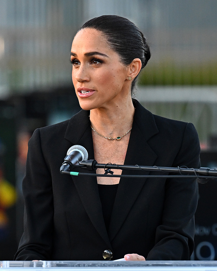 Meghan Markle making a complaint while speaking at a podium. Meghan Markle making a complaint while speaking at a podium.