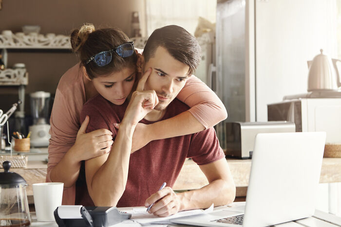 Woman hugging stressed man working on laptop, showing toxic relationship signs