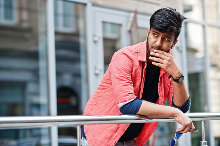 Man in red shirt appearing worried and contemplative about toxic love traits