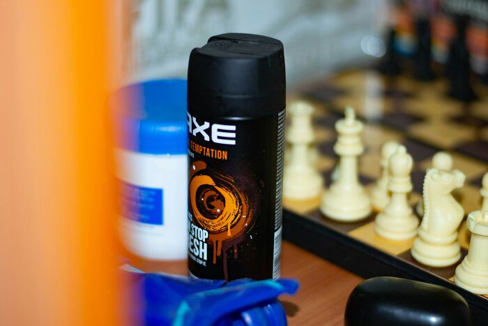 Axe body spray can placed near a chessboard and other items