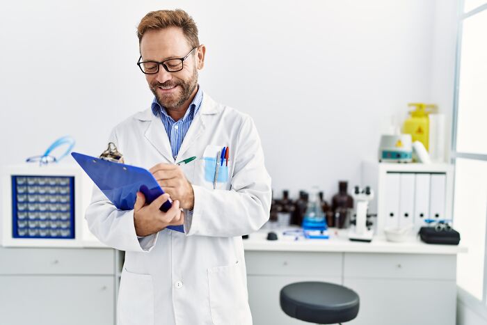 A male doctor smiling while looking at a clipboard in his laboratory