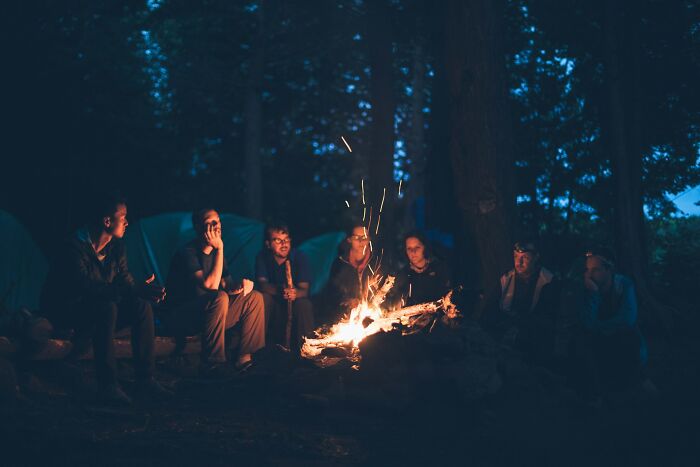 Friends gathered around a campfire at night, sharing stories and enjoying the cool facts about the universe's natural beauty.