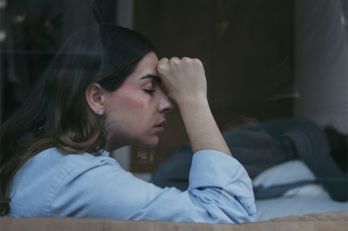 A woman looking stressed, experiencing the shock of her life, realizing her MIL's anger.