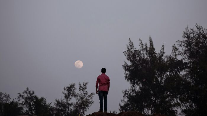 Man standing under a moonlit sky, reflecting on stupid things people said, and their ridiculousness.