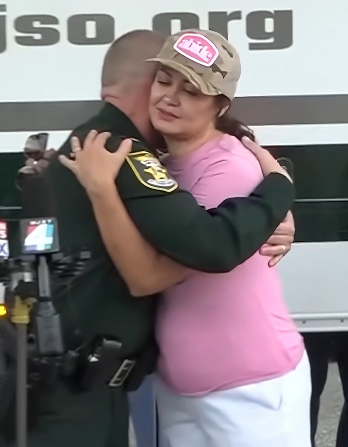 The mom receives a hug from the officer, her expression suggests her reaction is raising eyebrows.