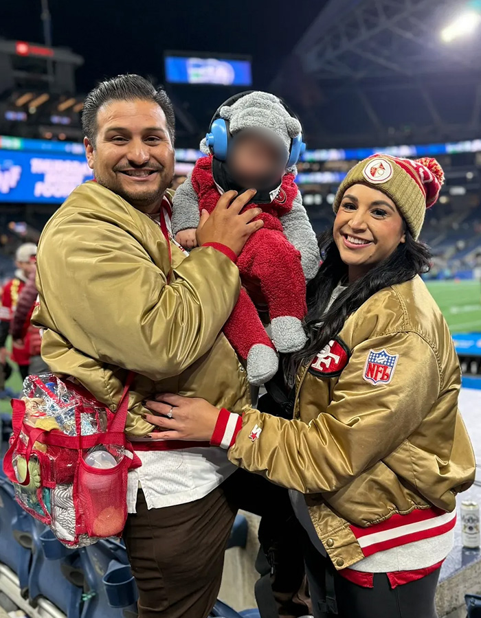 Family dressed in San Francisco 49ers gear at NFL game with baby
