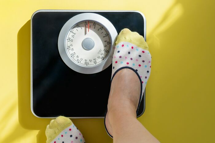 A person stepping on a scale representing weight changes, one of the common body changes in 30s and 40s