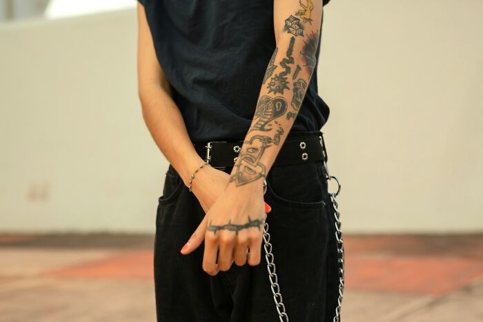 A person with tattooed arms and a chain on their pants, showcasing a unique style often seen in legal excuse cases.