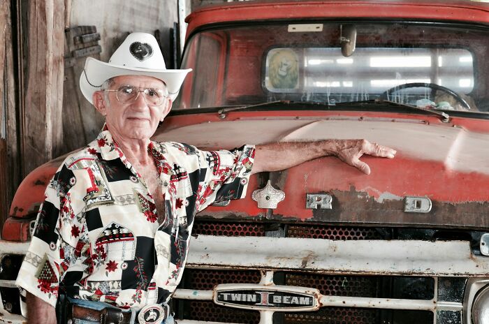 An older man in a cowboy hat leaning on an old truck, a visual for unusual legal excuses.