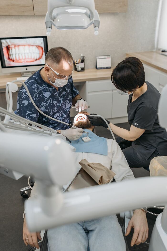 A dentist and assistant working on a patient, relating to legal excuses for medical appointments.