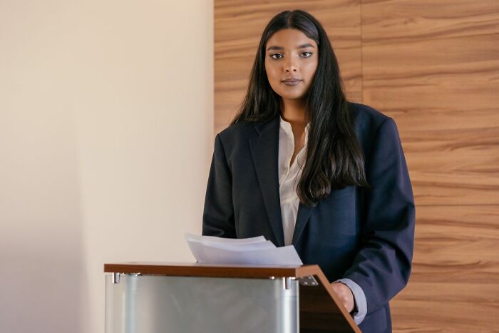 A professional woman at a podium, possibly preparing to present a legal excuse.