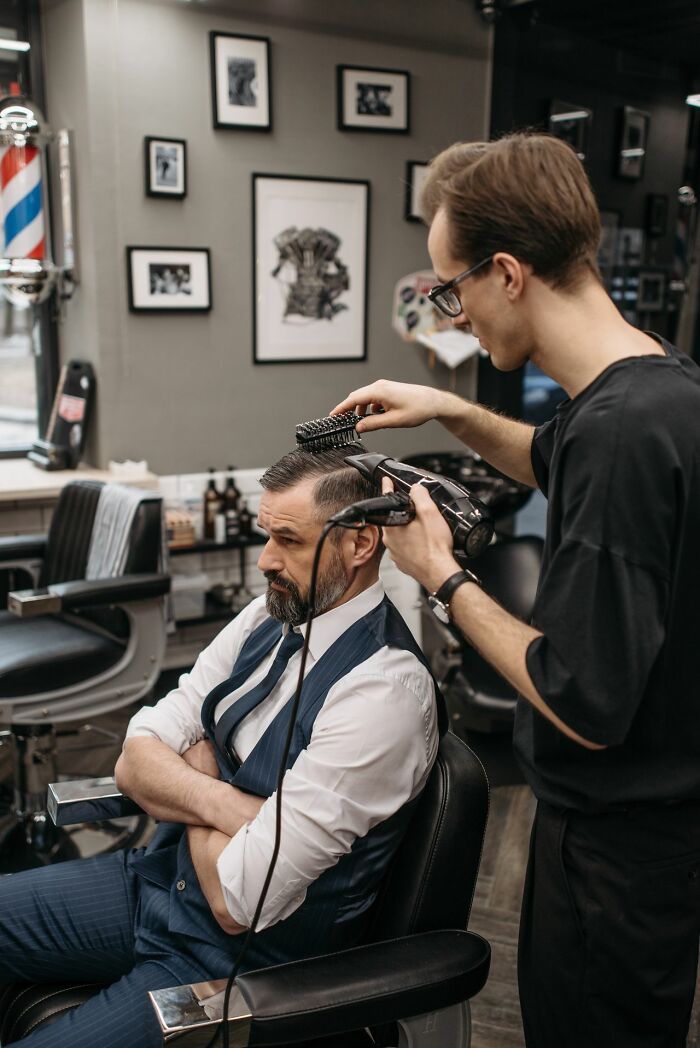 A man in a suit gets a haircut, an activity that could be a legal excuse for missing a commitment.
