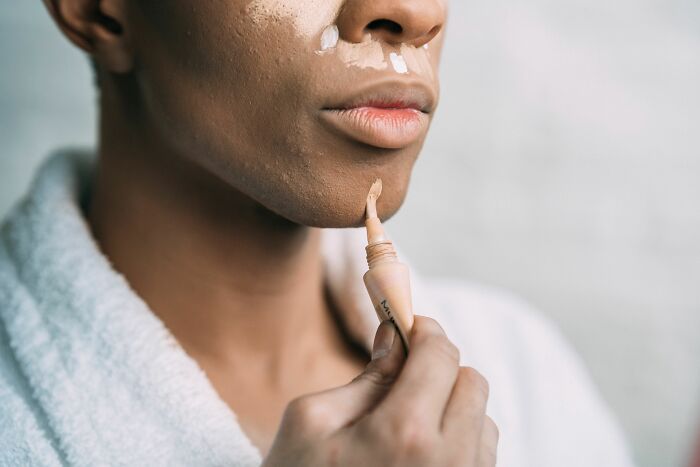 Person applying concealer, a self-care act reflecting changes and focus during a midlife crisis.