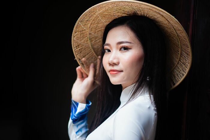 A young woman in a traditional hat and white dress, embracing new styles during a midlife crisis.