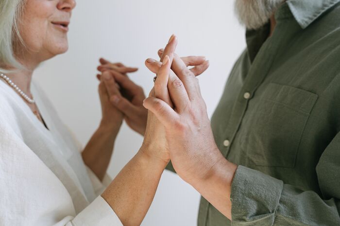 An older couple gently holding hands, symbolizing connection during a midlife crisis.