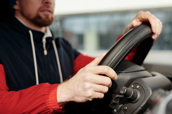 A man with a beard driving, representing new beginnings and a midlife crisis.