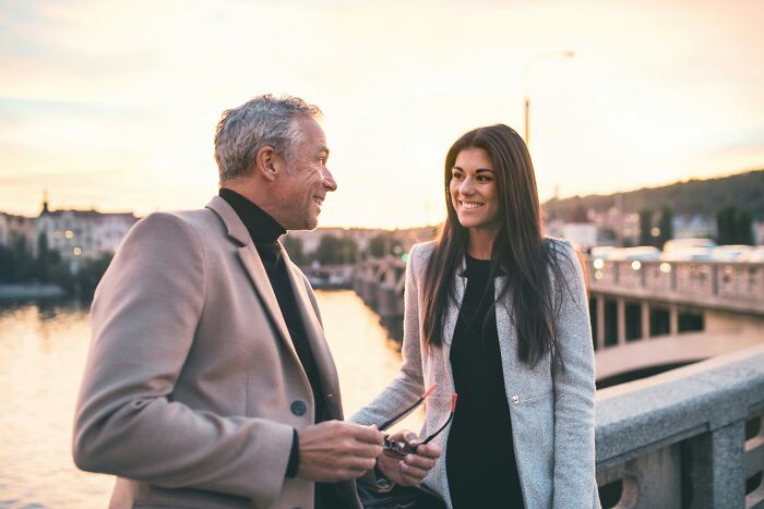 A man and a woman smiling at each other on a bridge, possibly reflecting a dating experience or a midlife crisis.