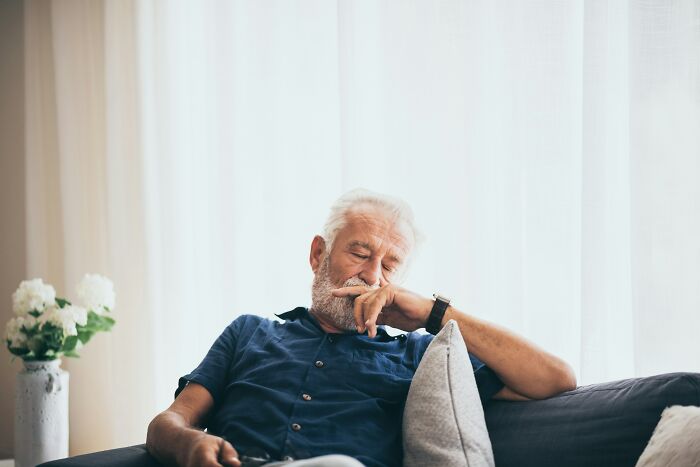 Elderly man sleeping on a couch, experiencing a midlife crisis.