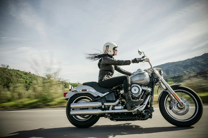 Woman riding a motorcycle on a highway, embracing her midlife crisis.