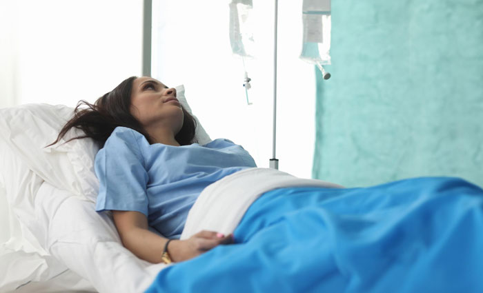 A young woman in a hospital gown lies in bed with an IV drip, considering her toxic boyfriend and child. A young woman in a hospital gown lies in bed with an IV drip, considering her toxic boyfriend and child.