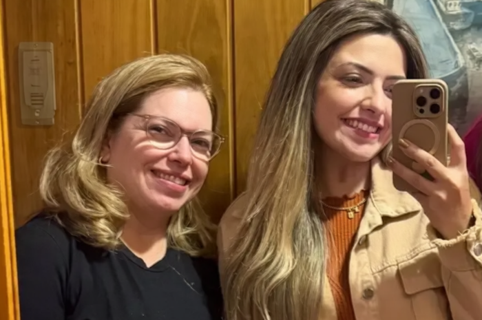 A mother and daughter smiling while taking a selfie together in an elevator.