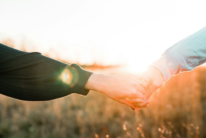 Two people holding hands at sunset, symbolizing a shared wish between mother and daughter.