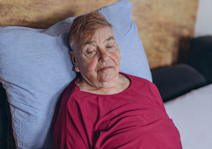 An older woman with a sad expression, representing a Toxic Mom neglecting her health.