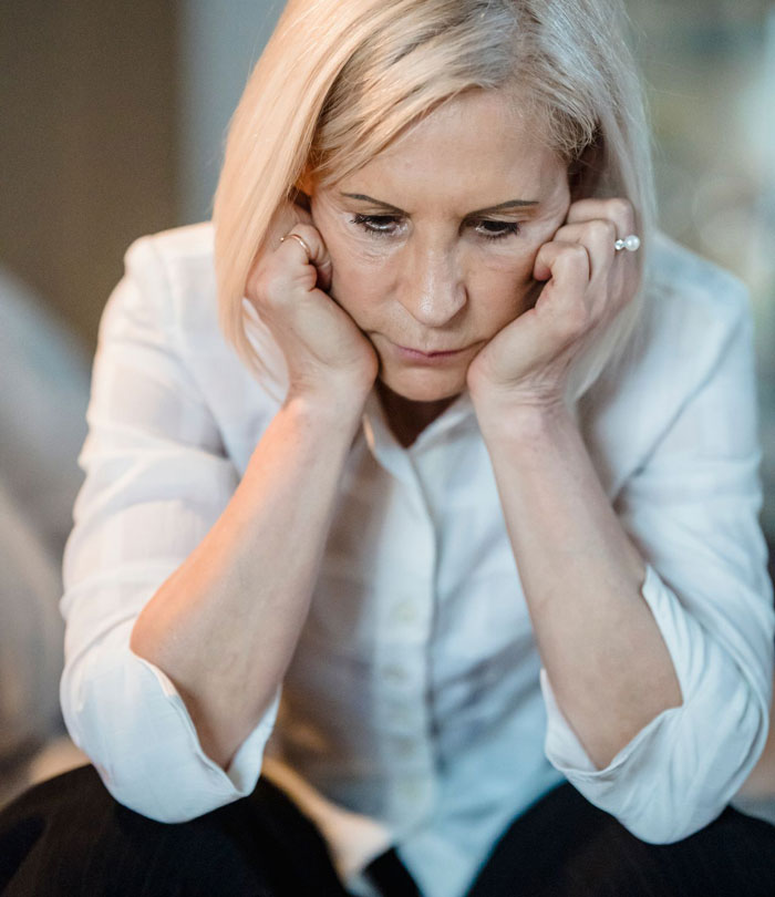 A thoughtful mom making an inheritance decision for her sons. The mom is looking down in thought. A thoughtful mom making an inheritance decision for her sons. The mom is looking down in thought.