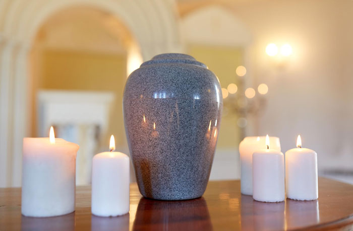 A grey urn surrounded by lit candles, symbolizing a funeral and the context of a prison break. A grey urn surrounded by lit candles, symbolizing a funeral and the context of a prison break.
