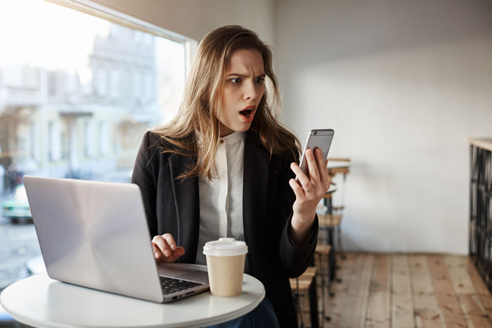 A woman looking shocked while holding her phone, illustrating the victim's reaction to the prison break situation. A woman looking shocked while holding her phone, illustrating the victim's reaction to the prison break situation.