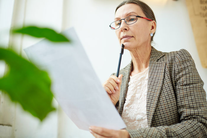 Woman in glasses holding documents, reflecting on the prison break events of the mom and aunt. Woman in glasses holding documents, reflecting on the prison break events of the mom and aunt.