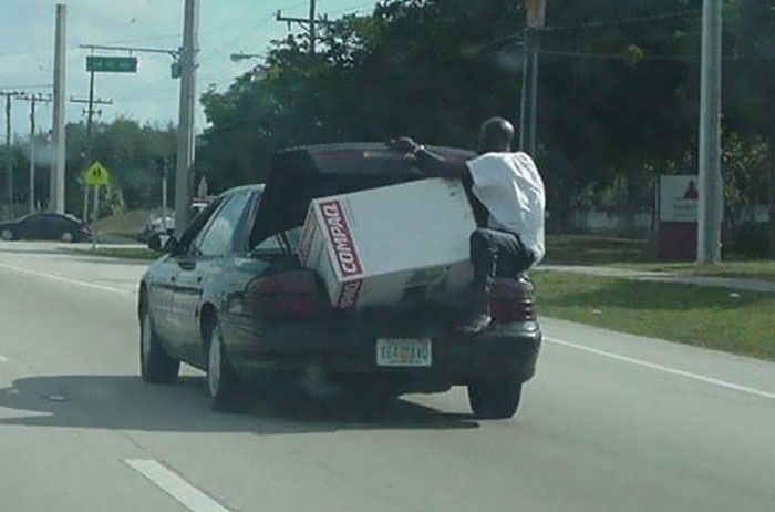 Man hanging on car trunk while transporting large box in moving fails pics