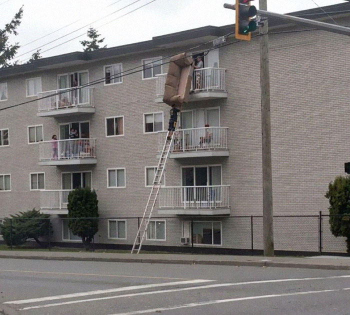 Moving fails with people precariously lifting couch through apartment balcony