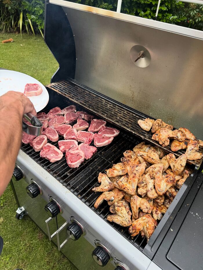 A man grilling various meats, including lamb chops and chicken wings, for a meat-only diet. A man grilling various meats, including lamb chops and chicken wings, for a meat-only diet.