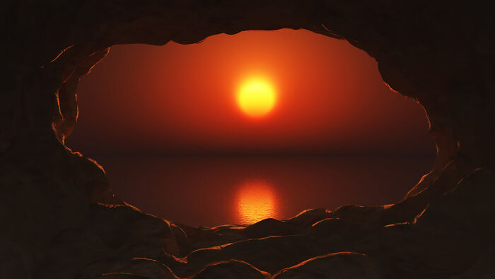 Eerie ancient entrance to hell in a cave opening, with a bright orange sunset over a calm body of water. Eerie ancient entrance to hell in a cave opening, with a bright orange sunset over a calm body of water.