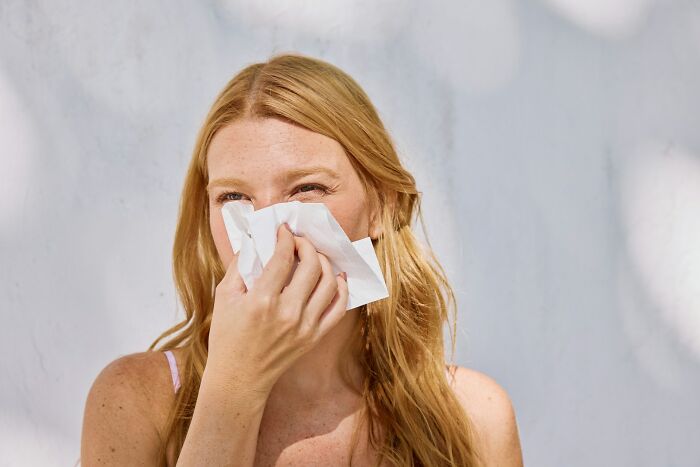 A blonde woman experiences allergy symptoms, illustrating body changes in their 30s and 40s.