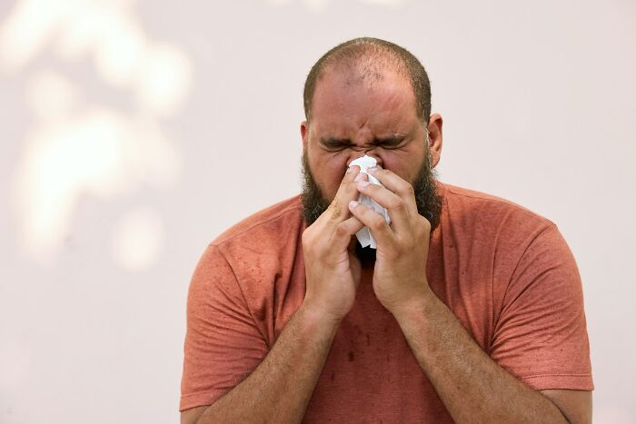 Man blowing his nose, a common action that things people do leads to others judging them for.